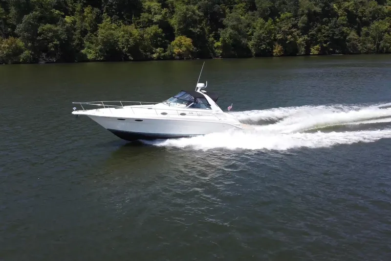 Slide: The Image of 1995 Sea Ray 330 Sundancer cruising on a scenic lake with lush green trees. - 4