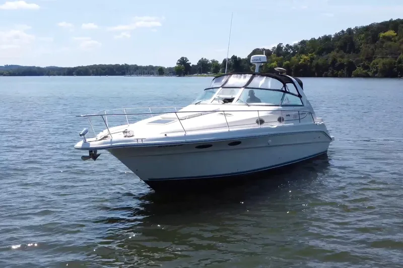 Slide: The Image of 1995 Sea Ray 330 Sundancer boat cruising on a serene lake with forested shoreline. - 5