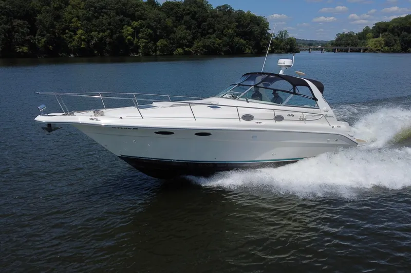 Slide: The Image of 1995 Sea Ray 330 Sundancer cruising on a scenic river with lush green trees. - 6