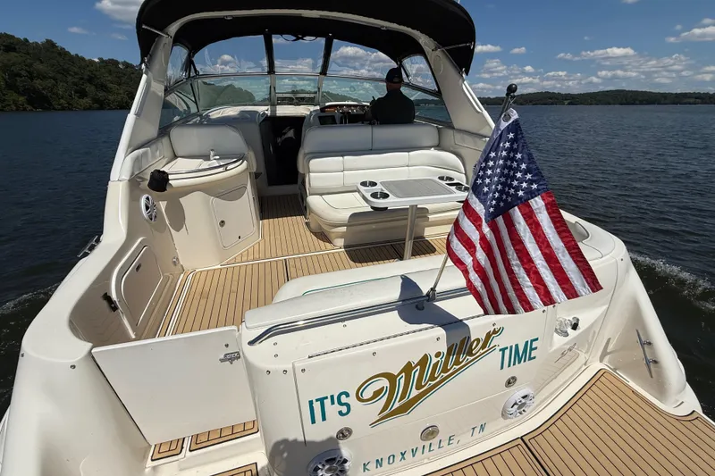 Slide: The Image of 1995 Sea Ray 330 Sundancer boat with American flag, cruising on a lake. - 8