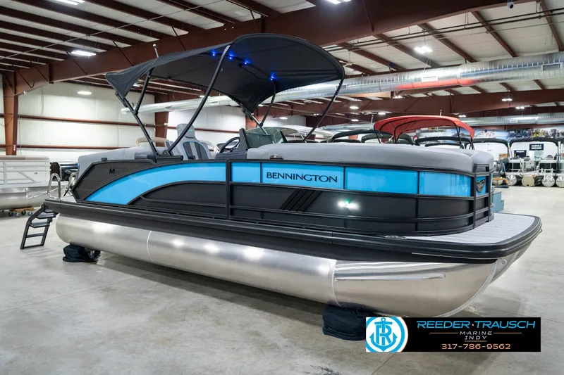 Slide: The Image of 2026 Bennington 22 MFB pontoon boat in showroom, featuring sleek design and blue accents. - 59