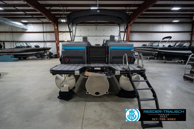 Slide: The Image of 2026 Bennington 22 MFB pontoon boat in indoor showroom with ladder and seating. - 9