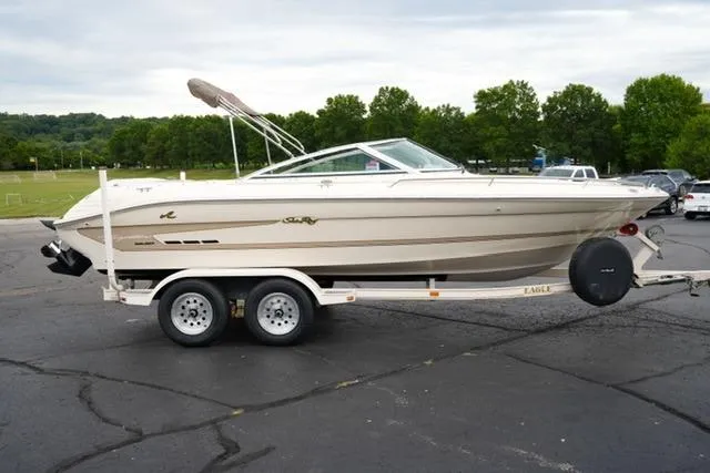 Slide: The Image of 1995 Sea Ray 200 Select boat on trailer in parking lot, surrounded by trees. - 3