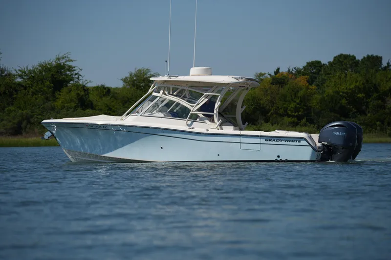 Slide: The Image of 2023 Grady-White Freedom 285 boat on calm water, surrounded by lush greenery. - 10