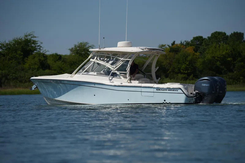 Slide: The Image of 2023 Grady-White Freedom 285 boat cruising on a calm lake with lush greenery. - 11