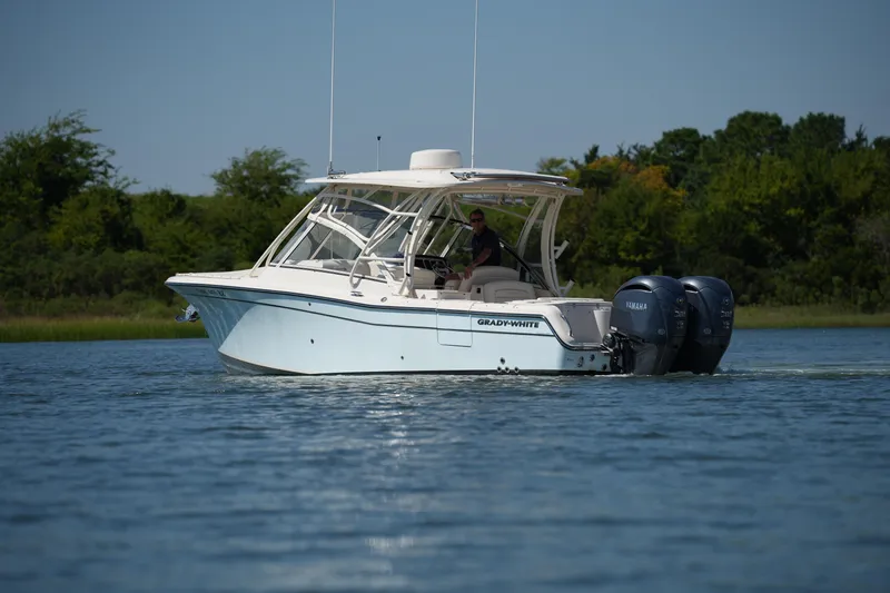 Slide: The Image of 2023 Grady-White Freedom 285 boat cruising on a calm lake with lush greenery. - 12
