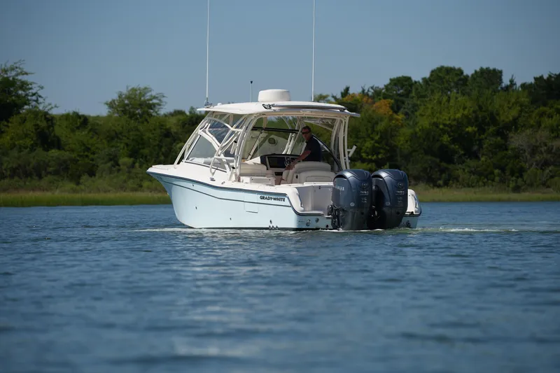 Slide: The Image of 2023 Grady-White Freedom 285 boat cruising on a serene lake with lush greenery. - 13