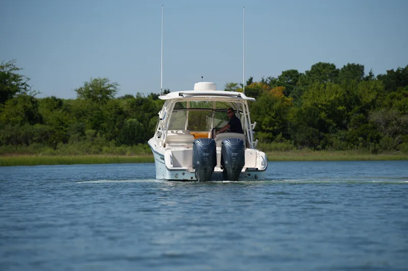 Slide: The Image of 2023 Grady-White Freedom 285 boat cruising on a calm lake with lush green shoreline. - 15