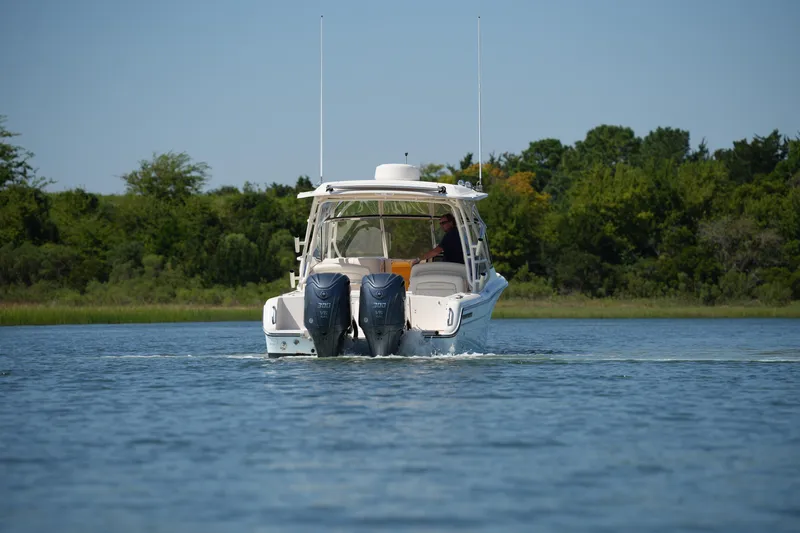 Slide: The Image of 2023 Grady-White Freedom 285 boat cruising on a calm lake with lush greenery. - 16