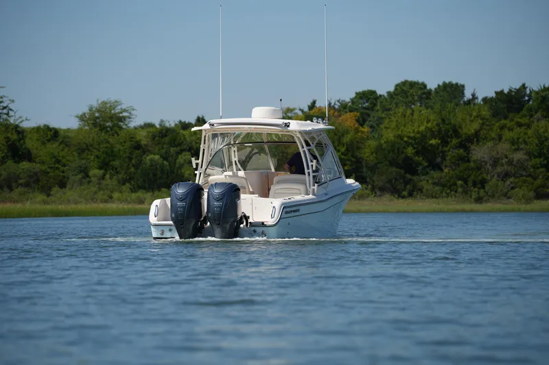 Slide: The Image of 2023 Grady-White Freedom 285 boat cruising on a calm lake with lush green shoreline. - 17