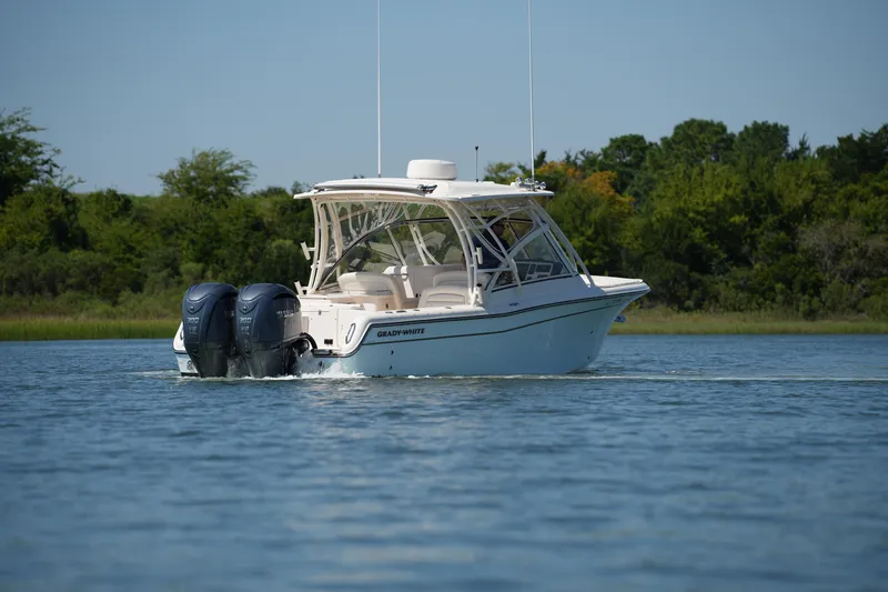 Slide: The Image of 2023 Grady-White Freedom 285 boat cruising on a calm lake with lush green shoreline. - 18