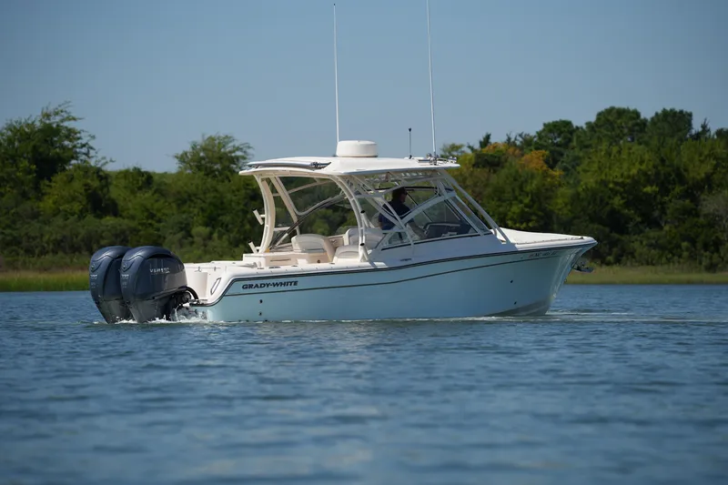 Slide: The Image of 2023 Grady-White Freedom 285 boat cruising on a calm lake with lush green background. - 19