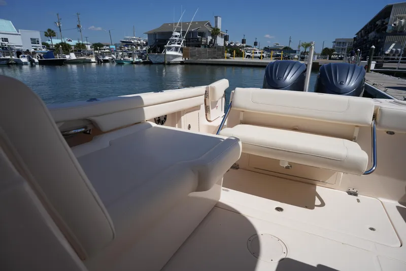 Slide: The Image of 2023 Grady-White Freedom 285 boat interior at marina, featuring comfortable seating and twin engines. - 30