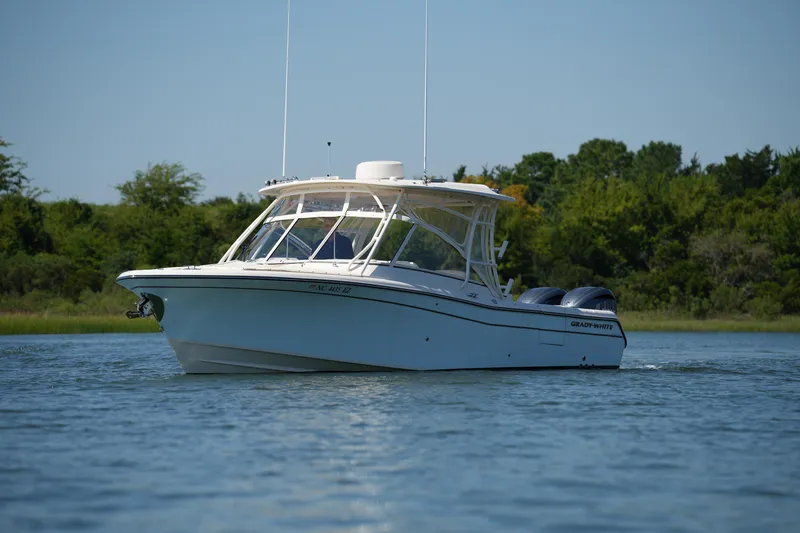 Slide: The Image of 2023 Grady-White Freedom 285 boat cruising on a calm lake with lush greenery. - 4