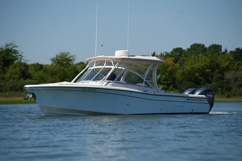 Slide: The Image of 2023 Grady-White Freedom 285 boat cruising on a calm lake with lush greenery. - 5