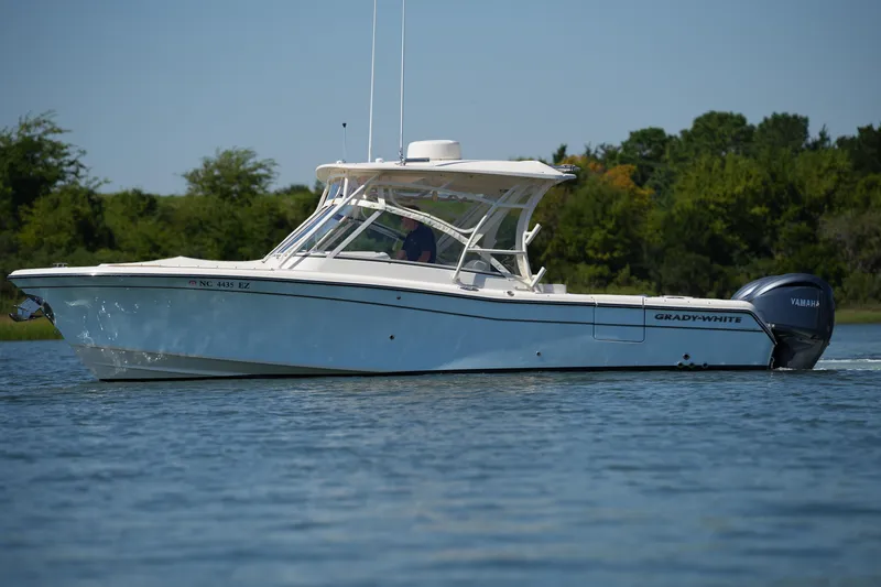 Slide: The Image of 2023 Grady-White Freedom 285 boat cruising on a calm lake with lush green background. - 8