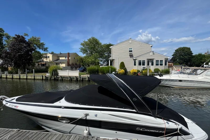 The Image of 2012 Crownline 305 SS boat docked by a waterfront house under a clear blue sky. - 1