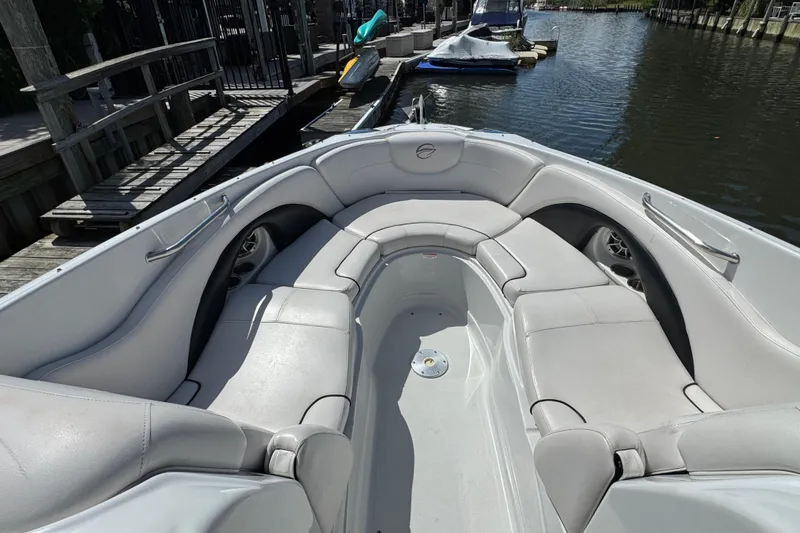 Slide: The Image of 2012 Crownline 305 SS boat with spacious seating, docked by a calm waterway. - 17