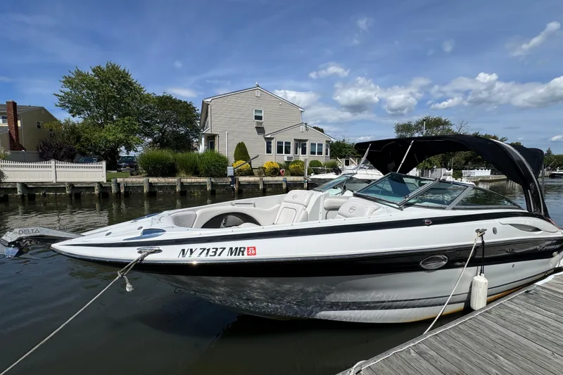 Slide: The Image of 2012 Crownline 305 SS boat docked by a waterfront home under a clear blue sky. - 31