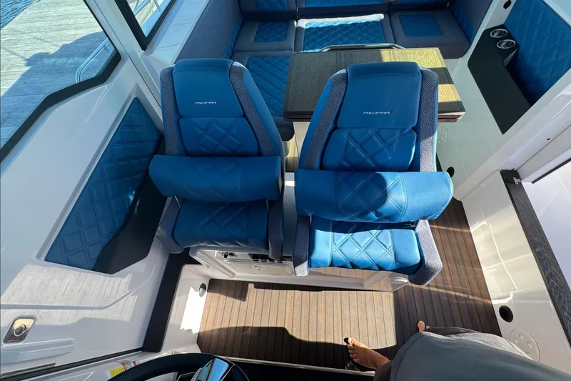 Slide: The Image of 2024 Axopar 37 XC CROSS CABIN interior with blue seating and wood flooring. - 13