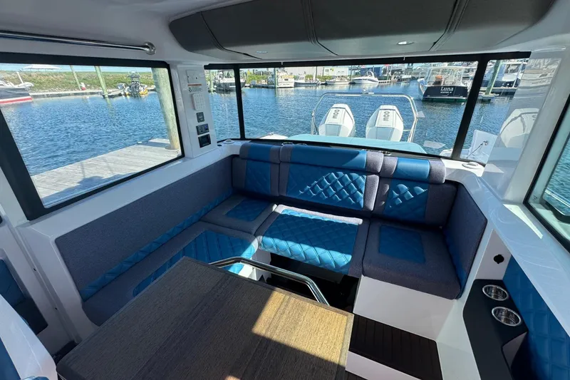 Slide: The Image of Interior of 2024 Axopar 37 XC CROSS CABIN with blue seating and waterfront view. - 14