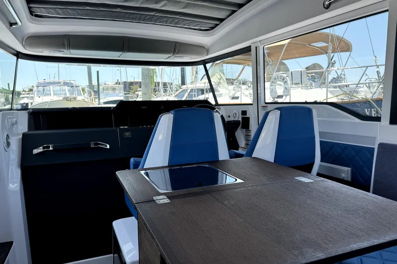 Slide: The Image of 2024 Axopar 37 XC CROSS CABIN interior with blue seating and wooden table. - 15