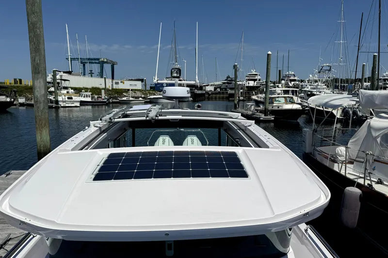 Slide: The Image of 2024 Axopar 37 XC CROSS CABIN docked in a marina, featuring a solar panel on the roof. - 2