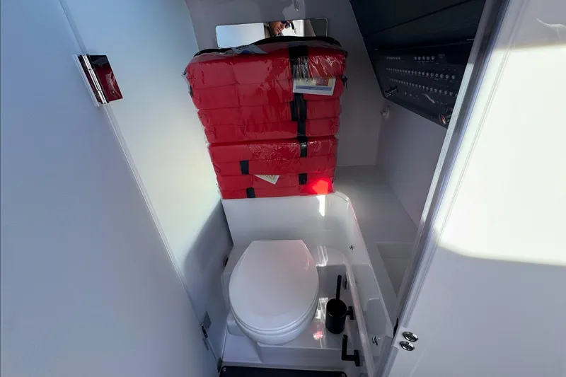 Slide: The Image of 2024 Axopar 37 XC CROSS CABIN bathroom with toilet and red life jackets. - 25