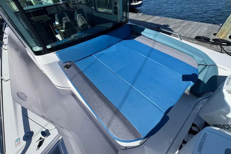 Slide: The Image of 2024 Axopar 37 XC CROSS CABIN with blue sunbed, docked by the water. - 6