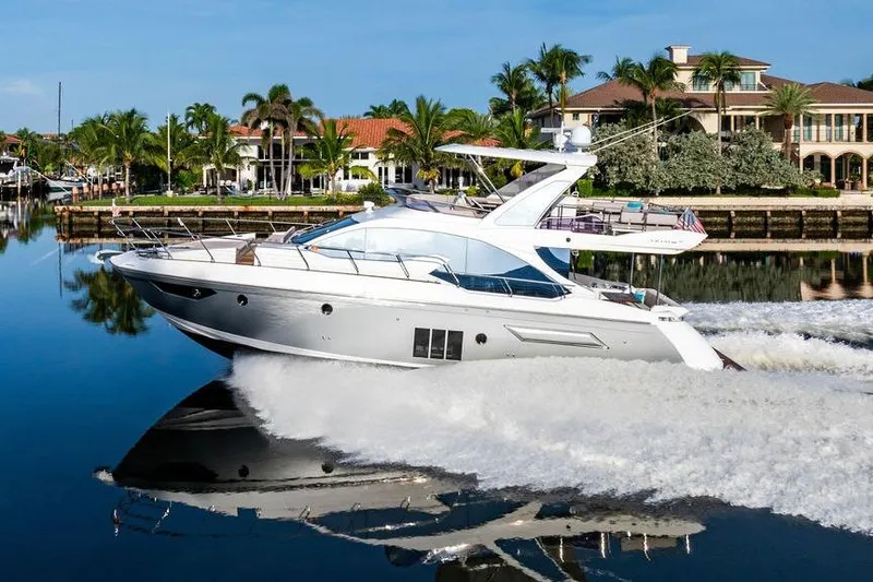 Slide: The Image of 2015 Azimut Fly 50 yacht cruising on a serene waterway with luxury homes in the background. - 19