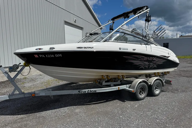 The Image of 2008 Yamaha Boats 212X on trailer, parked outside a warehouse under a cloudy sky. - 1