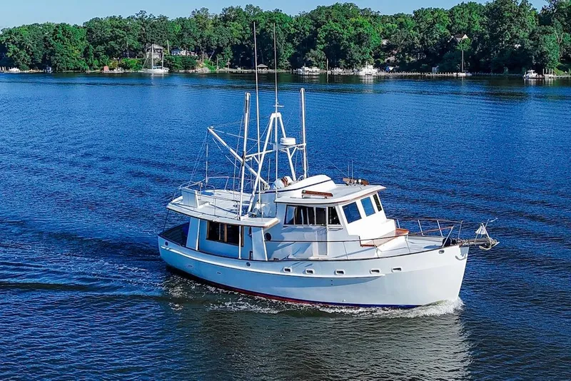 The Image of 1983 Kadey-Krogen Krogen 42 Trawler cruising on a serene lake with lush green shoreline. - 0