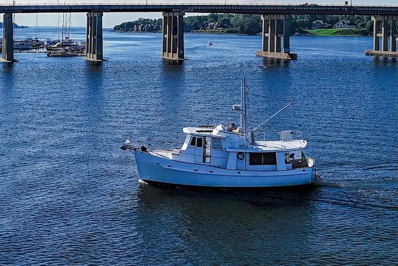 Slide: The Image of 1983 Kadey-Krogen Krogen 42 Trawler cruising under a bridge on a sunny day. - 1