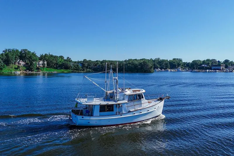 Slide: The Image of 1983 Kadey-Krogen Krogen 42 Trawler cruising on a serene lake under clear blue skies. - 2