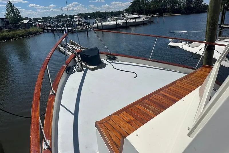 Slide: The Image of 1983 Kadey-Krogen Krogen 42 Trawler docked, showcasing wooden deck and scenic marina view. - 7