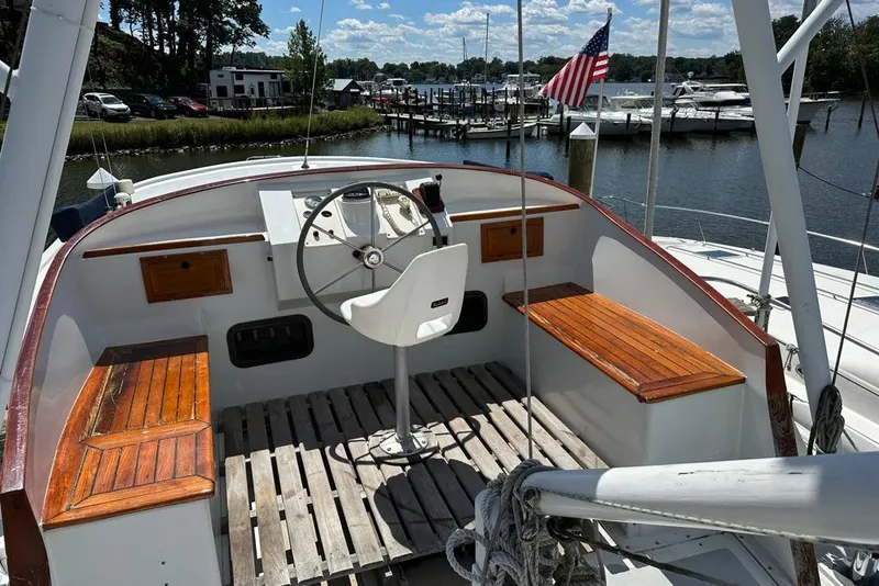 Slide: The Image of 1983 Kadey-Krogen Krogen 42 Trawler helm with wooden benches, docked by a marina. - 9