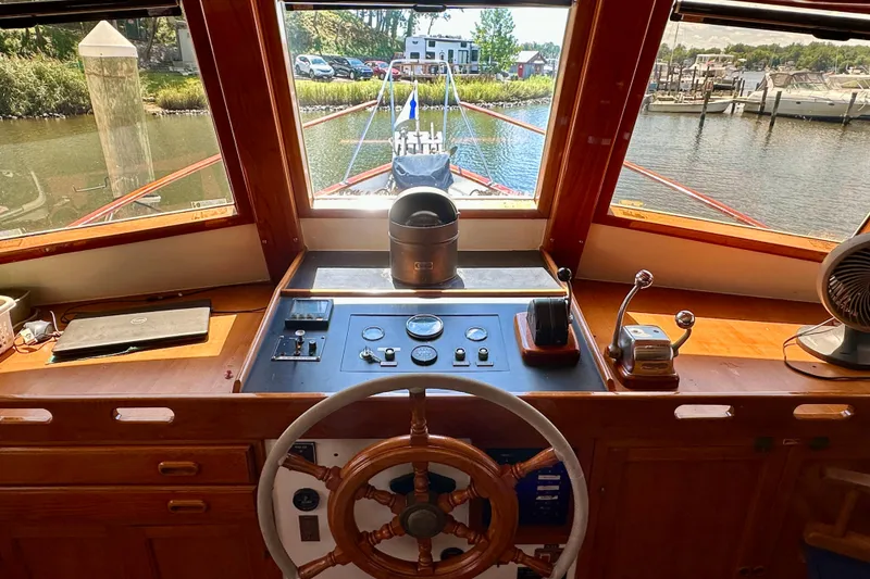 Slide: The Image of 1983 Kadey-Krogen Krogen 42 Trawler helm with wooden wheel and control panel, docked in marina. - 14