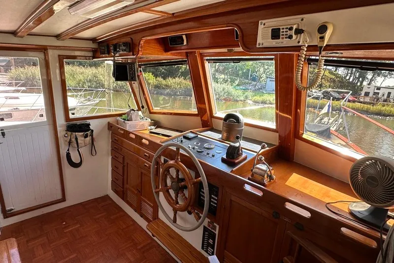 Slide: The Image of 1983 Kadey-Krogen Krogen 42 Trawler helm with wooden wheel, controls, and river view. - 15