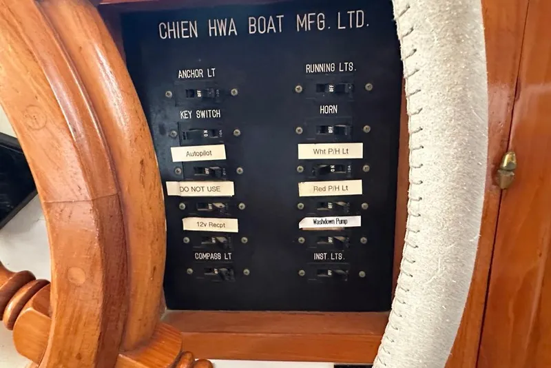 Slide: The Image of Control panel of 1983 Kadey-Krogen Krogen 42 Trawler with labeled switches and wooden wheel. - 19