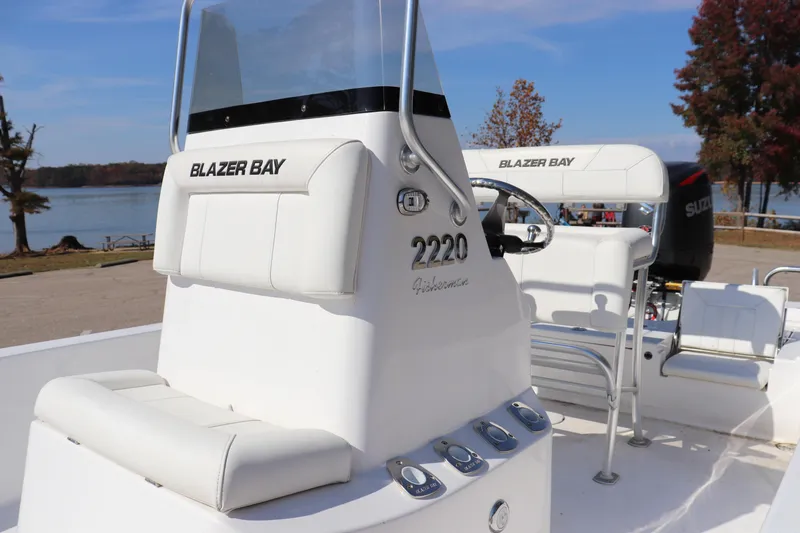 Slide: The Image of 2024 Blazer Bay 2220 Fisherman boat, white interior, parked by a scenic lakeside. - 7