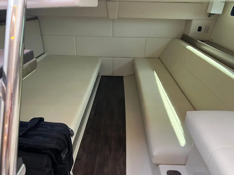 Slide: The Image of 2022 Regal 36GC boat interior with white seating and cup holders, docked near a warehouse. - 10