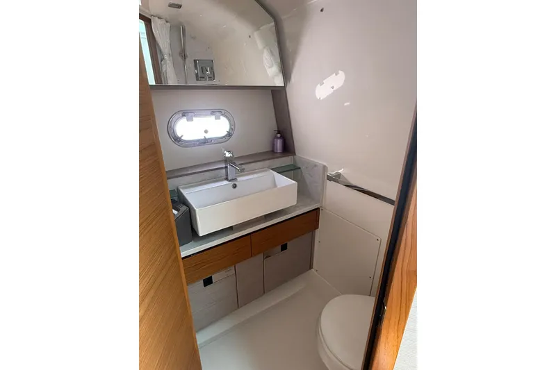 Slide: The Image of 2024 Tiara Yachts 38 LS bathroom with modern sink, toilet, and porthole window. - 21
