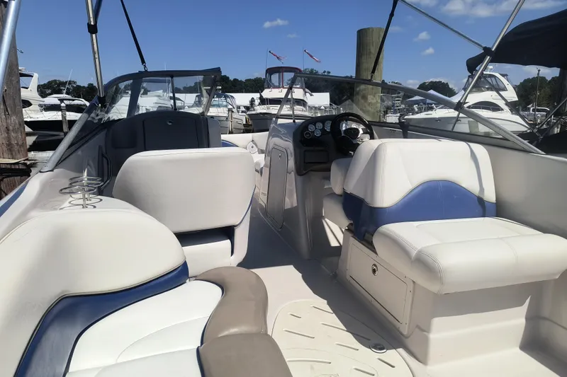 Slide: The Image of 2005 Tahoe 254 boat interior with white and blue seating at a marina. - 7