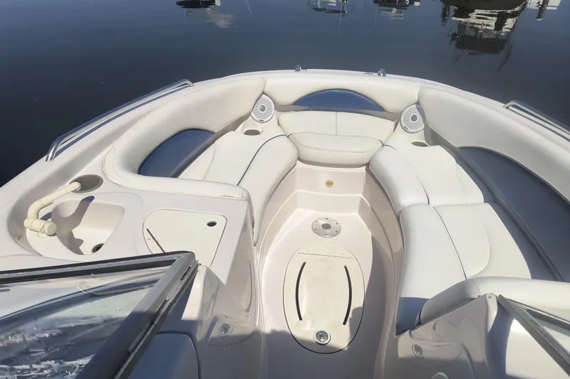 Slide: The Image of 2005 Tahoe 254 boat interior with white seating and cup holders on calm water. - 8