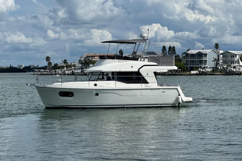 Slide: The Image of 2023 Beneteau Swift Trawler 35 cruising on a calm waterway with scenic background. - 12