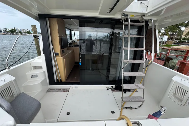 Slide: The Image of 2023 Beneteau Swift Trawler 35 cockpit with ladder and sliding glass door, dockside view. - 21