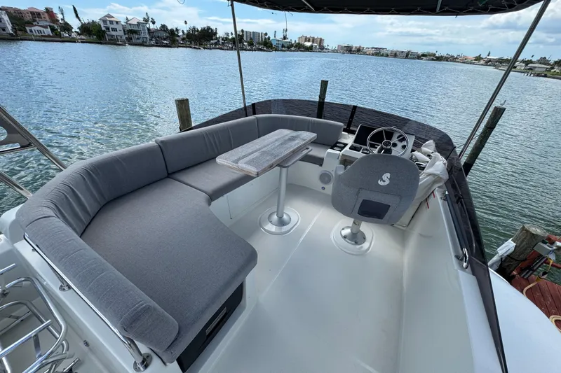 Slide: The Image of 2023 Beneteau Swift Trawler 35 flybridge with seating and helm, overlooking serene waterfront. - 22