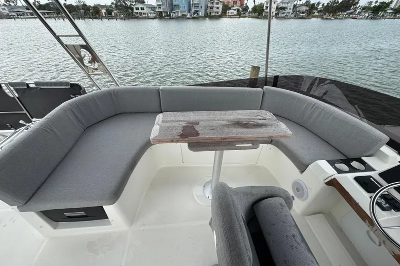 Slide: The Image of 2023 Beneteau Swift Trawler 35 cockpit with gray seating and wooden table, overlooking waterfront homes. - 26
