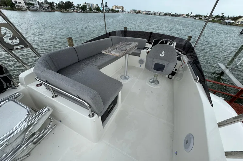 Slide: The Image of 2023 Beneteau Swift Trawler 35 flybridge with seating, table, and helm, overlooking water. - 27