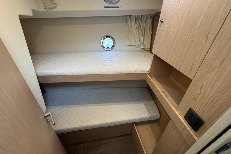 Slide: The Image of 2023 Beneteau Swift Trawler 35 cabin with bunk beds and wooden storage. - 42